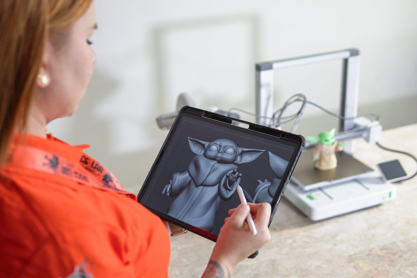 Alexandra López, diseñadora 3D de Space Lab, modela una figura en su tableta junto a una impresora 3D