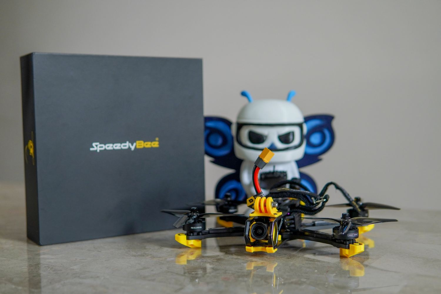 Dron FPV SpeedyBee junto a la figura de la mascota
